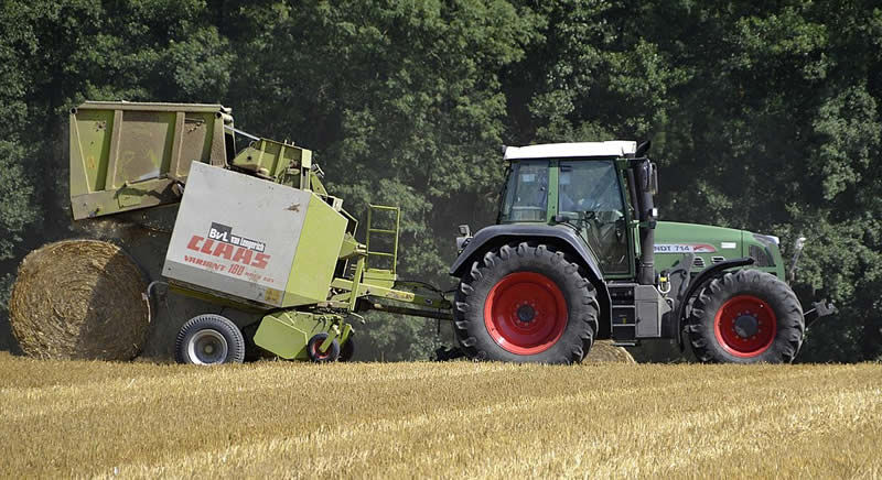 A Fendt 714 Vario with a hay baler on a field in Bavaria, Germany